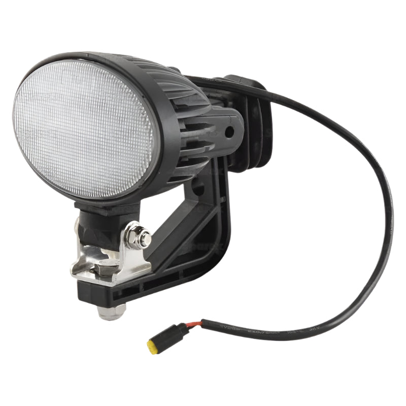 The New Holland LED Work Light by Sparex, model S.163877, is a black oval-shaped work light featuring a flood beam, mounting bracket, and an attached power cable. It delivers 4500 lumens of raw light output and operates within a voltage range of 10-30V. Designed to meet IP6K9K standards for extreme durability and classified as Interference Class 5.