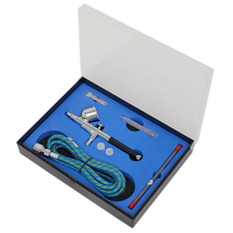 The Sealey Air Brush Kit Gravity Feed - AB9321 features a metal body, double-action trigger, 0.3mm nozzle, hose, cleaning brush, pipette, wrench, and two small containers all neatly packaged in a foam-lined box with a transparent lid.