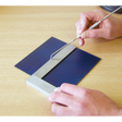 A person uses the Sealey Precision Steel Square 150mm - AK11150 to examine a blue material resting on a flat surface, alongside a metal ruler.