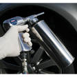 A gloved hand holds Sealey's Air Underbody Coating Gun - AK42, connected to a regulator set at 90psi, aimed at the tire of a vehicle.