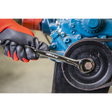 A gloved hand from the Sealey Combination Spanner Set 12pc - Metric - AK63265 uses a wrench to tighten a bolt on a mechanical assembly, showcasing the reliable strength of chrome vanadium steel.