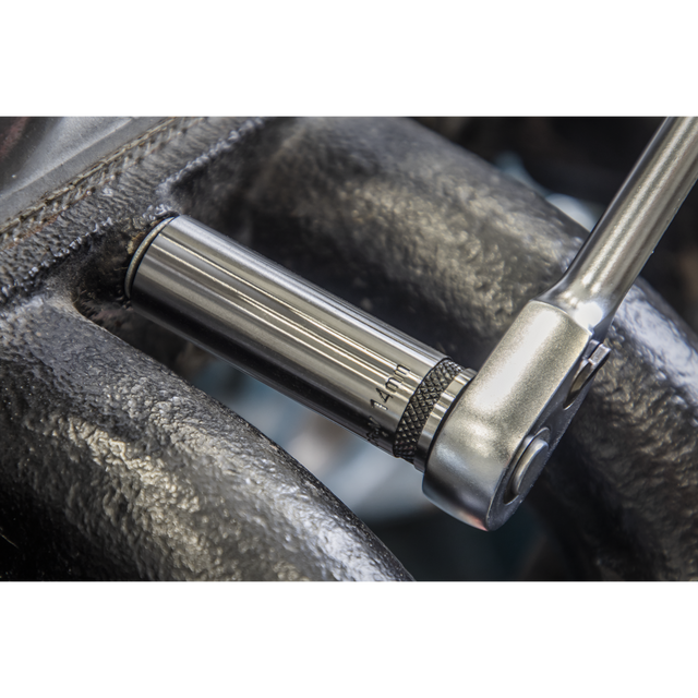 Close-up of a Sealey Socket Set Deep 12pc 3/8"Sq Drive Metric - Black Series - AK7993 ratchet wrench, crafted from durable Chrome Vanadium steel, tightening a bolt. The sleek, metallic wrench contrasts with the rough, textured surface of the surrounding material and ensures longevity with a lifetime guarantee.