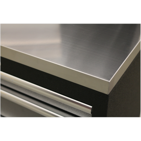 Close-up of a metal tool chest corner featuring the Sealey APMS50SSB Floor Cabinet with a Stainless Steel Worktop (1360mm) and a partially visible drawer with a handle underneath.