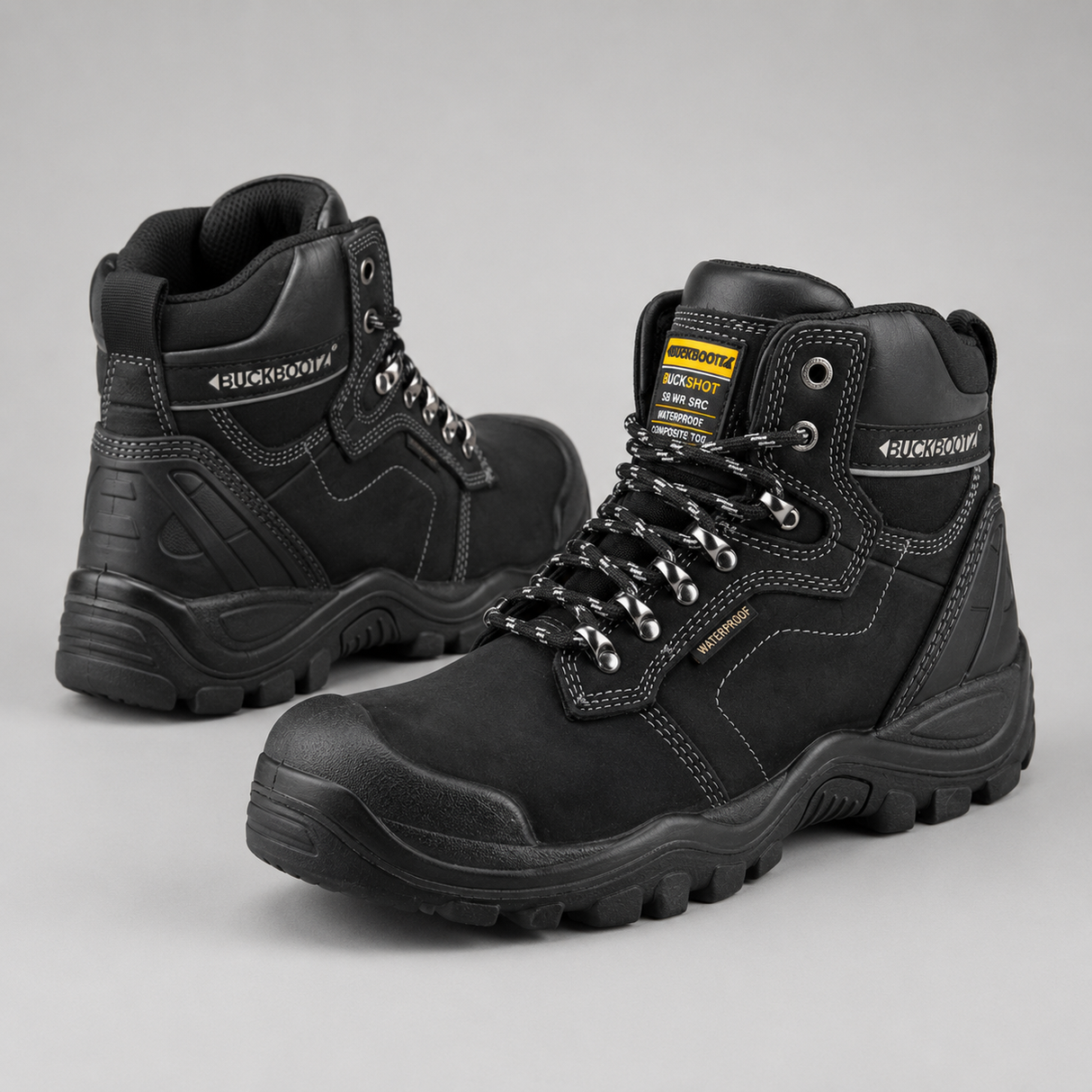 A pair of black high-top safety work boots with silver laces and a yellow and black tongue label, displayed on a neutral gray background.