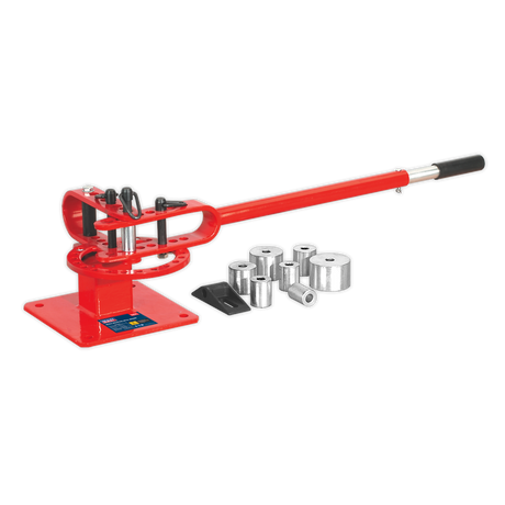 The Sealey Metal Bender Bench Mounting - PBB04, a red manual metal bender with a long handle and multiple interchangeable dies for creating radiused bends, is lying beside it on a white background.