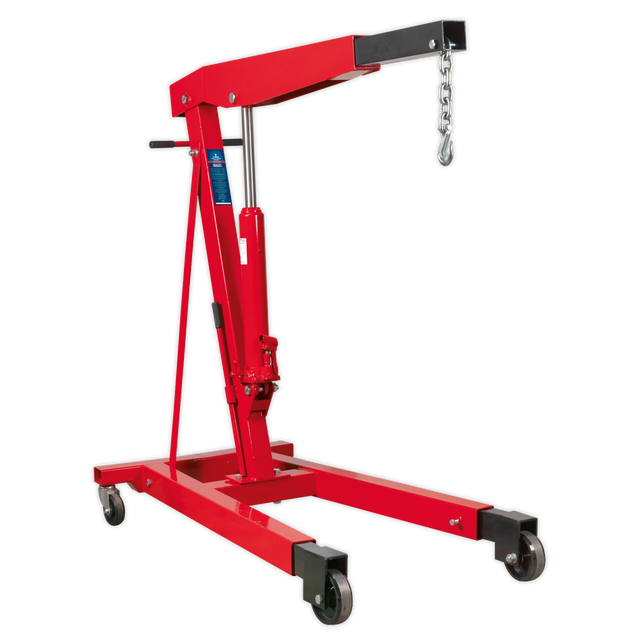 The Sealey Fixed Frame Engine Crane with Extendable Legs 3 Tonne - PH30 is a red hydraulic hoist featuring a lifting arm, hook, and chain. Designed for industrial use, it boasts a wheeled base with heavy-duty castors for mobility and an adjustable boom that can handle heavy engines and machinery up to a 3000kg lifting capacity.