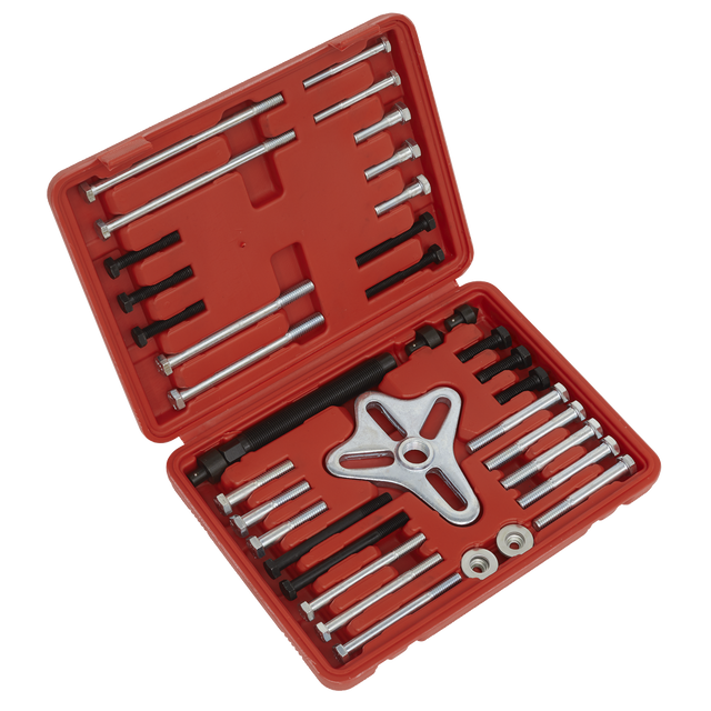 A red plastic storage case from Sealey, containing the Harmonic Balancer Puller Set 49pc - PS979, includes bolts, rods, and a three-pronged pulling device for extracting flywheels. The case is open to display the neatly organized tools.