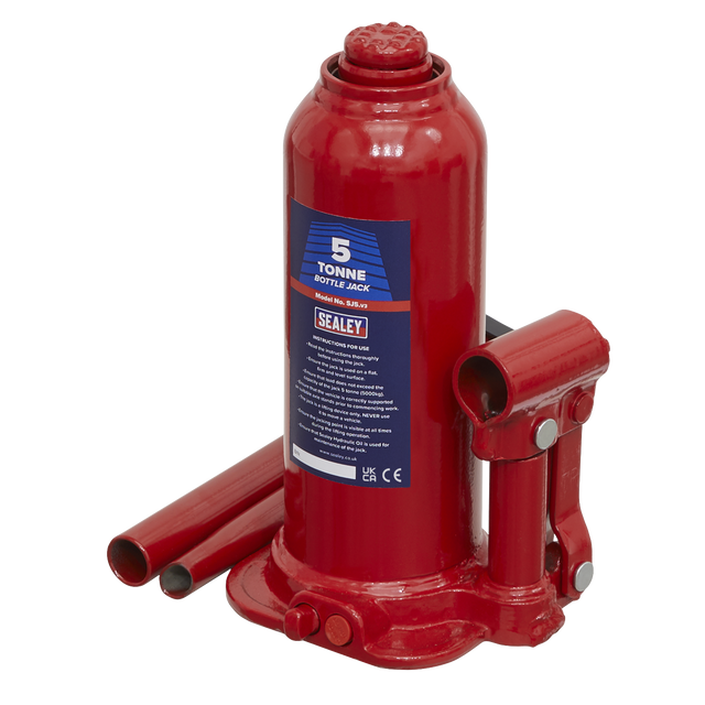 A red Sealey Bottle Jack 5 Tonne - SJ5 with a 2-piece handle and detached parts, designed for lifting heavy objects, featuring an overload valve for added safety.