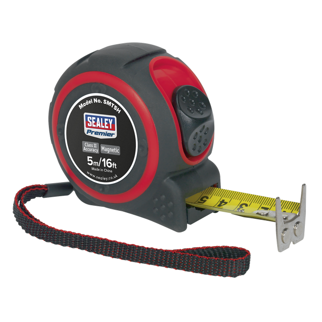 Introducing the Sealey Heavy-Duty Tape Measure 5m (16ft) - SMT5H: a highly durable black and red measuring tape from the Premier Hand Tools range, featuring a yellow metric/imperial rule tape, a magnetic tip, and an attached black wrist strap.