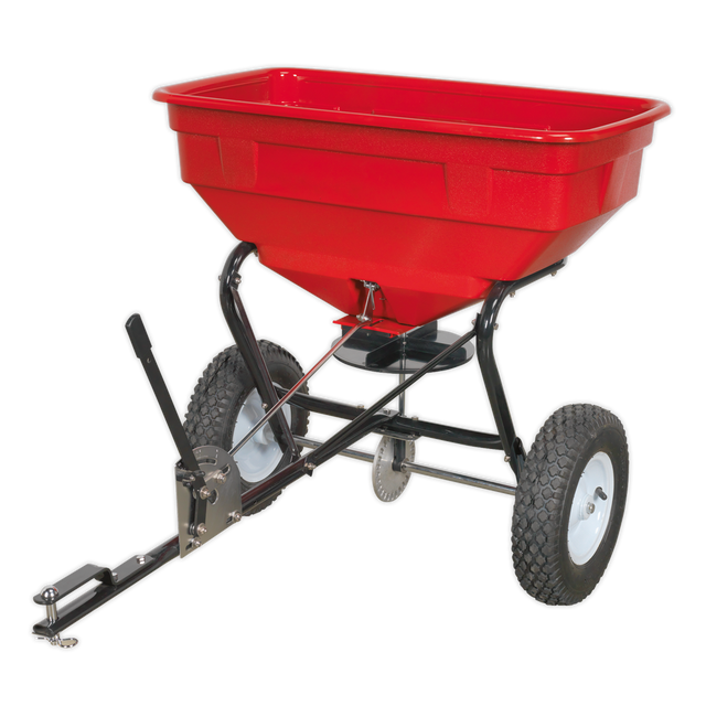 The Sealey Broadcast Spreader 57kg Tow Behind - SPB57T features an adjustable feed system and is designed with a red body, black frame, and two large white heavy-duty pneumatic tyres.