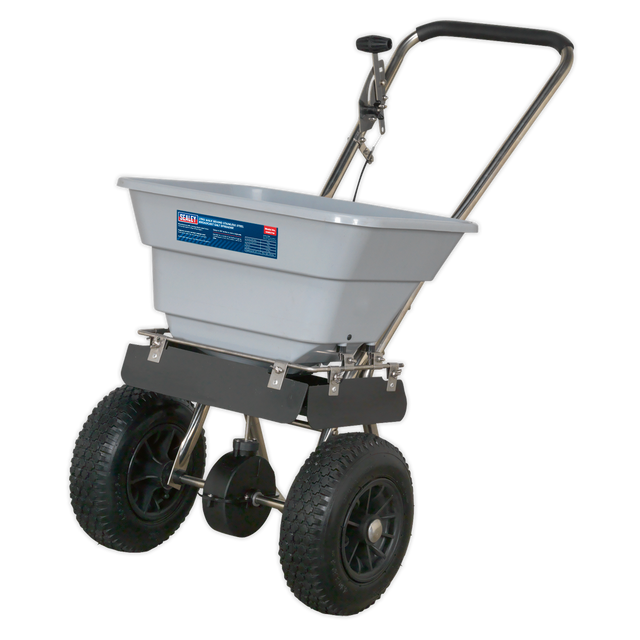 The Sealey Stainless Steel Broadcast Salt Spreader 37kg Walk Behind - SSB37W features a corrosion-resistant design with a gray hopper and black handle, ideal for distributing lawn treatments evenly over large areas. Equipped with pneumatic tires, this tool ensures easy maneuverability.