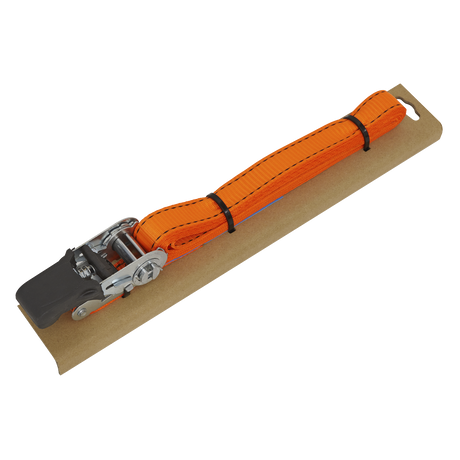 The Sealey Ratchet Tie Down 25mm x 5m Polyester Webbing with Corner Protector, featuring a durable polyester webbing and boasting a 600kg breaking strength, is secured on a rectangular piece of cardboard with a metal ratchet mechanism at one end.