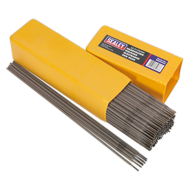 A yellow box of Sealey Welding Electrodes Hardfacing Ø2.5 x 300mm 5kg Pack - WEHF5025 is open, revealing several electrodes neatly packed inside and some laid out beside the box—ideal for repairs on agricultural and construction machinery.