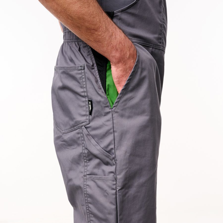 Close-up of a person wearing dark gray scrub pants with a side pocket and a green undershirt peeking out, against a plain white background.