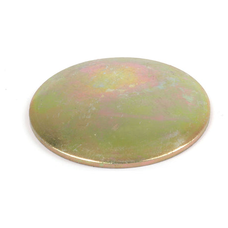 A round, flat metal disk with a slightly tarnished surface, displaying a mix of gold and green hues; it appears to be the Core Plug - 1 3/4'' (Dished Type - Mild Steel) from Sparex, commonly used in Ford/New Holland machinery.