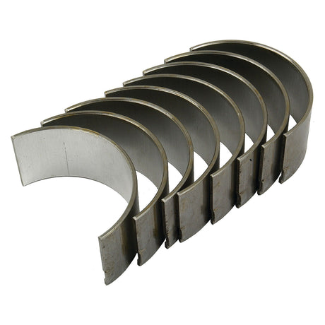 A curved, shiny metal component, identified as a Conrod Bearing Std. Set from an International Harvester machine by Sparex (Part No.S.57520), is displayed. Several identical pieces are stacked neatly in a fan-like arrangement, made of steel or similar metal.