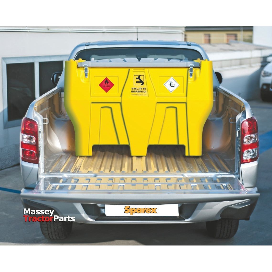 A Sparex Carrytank Pickup - 440L - Diesel - 12V (DC) - S.163021 with an automatic nozzle is secured in the cargo area of a silver pickup truck parked near a building. The yellow fuel tank features hazard symbols, branding labels, and UV protection.