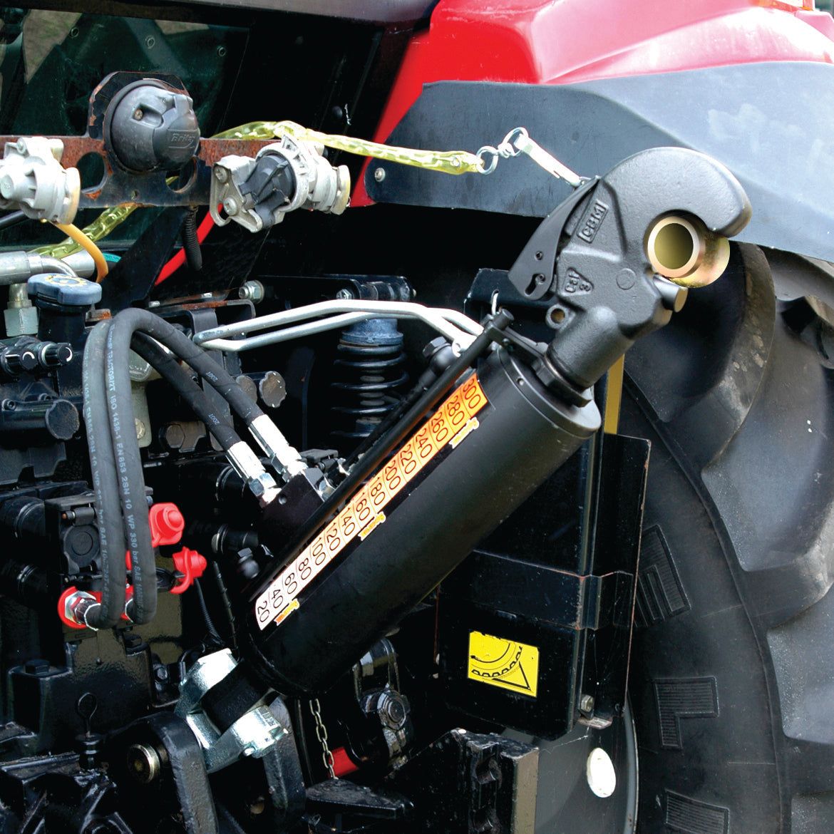 Close-up of the Sparex Hydraulic Top Link (Cat.3/3) Knuckle and Q.R CBM Hook, with a 90mm cylinder bore and a minimum length of 690mm, attached to the rear end of a red tractor. Various hoses and connection points are visible near the implement end.
