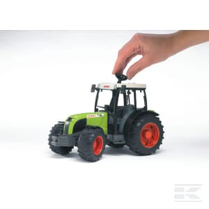 A hand is adjusting the knob on the roof of a green and black Claas Nectis 267 F - U02110 toy tractor from Bruder, featuring large red wheels, making it perfect for introducing little ones to the world of agriculture.