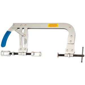 The Draper Valve Heavy Duty Spring Compressor, featuring a 35 - 142mm capacity and product code VSC6, is a large metallic C-clamp equipped with a blue locking handle and tightening screw mechanism. It also has a yellow warning label, making it ideal for maintenance work on valve springs.