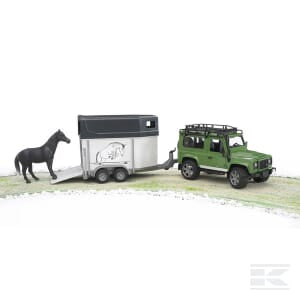 A green Land Rover Defor SUV, product U02592 by Bruder, is towing a silver horse box with a black horse standing beside it on a grassy area.