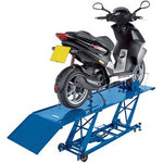 A black scooter is positioned on a blue Draper Hydraulic Motorcycle Lift, 360Kg - MCL1, elevated off the ground by a hydraulic pump, with a ramp extending from the lift.