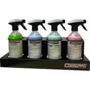 Four spray bottles containing different colored liquids (two green, one blue, and one pink) are neatly arranged in a JMCE "Chrome - 4 Bottle Holder." Each bottle is labeled with the product name and information.