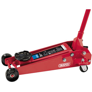 The Draper Heavy Duty Garage Trolley Jack, 3 Tonne, Red - TJ3HD/BR, is designed for lifting vehicles in an automotive workshop. It features a labeled handle and wheels, a heavy-duty chassis, and includes a safety valve for added security.