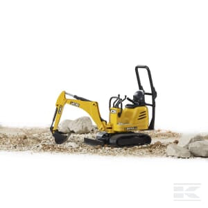 A Bruder JCB 8010 CTS micro digger (model U62003) sits on a rocky surface, surrounded by several large rocks, ready for construction work.