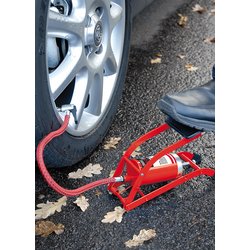 A foot is pressing down on the Draper Redline Foot Pump - RL-FP with its braided delivery hose, inflating the car tire. Fallen leaves are scattered on the ground.