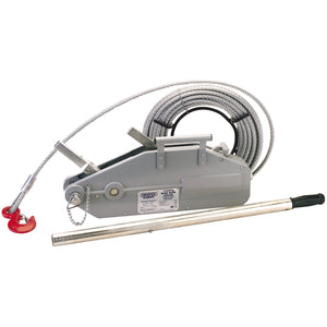 The Draper Expert Wire Rope Puller, 1600Kg - WRP1 by Draper is a portable manual cable winch that includes a sturdy metal housing, a coiled wire rope equipped with a red hook, and an easily detachable handlebar for operation.