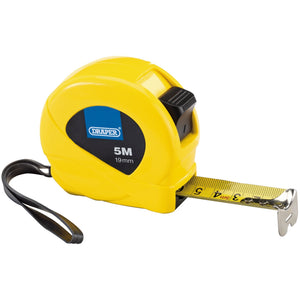 A Draper measuring tape from the HVMT/DBOX12 collection, in yellow with a 5-meter length and 19mm width, featuring clear graduations, a self-aligning end hook, a black wrist strap, and partially extended tape.