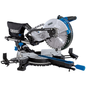 Image of the Draper 230V Sliding Compound Mitre Saw, model SMS250D1800, with a 255mm blade designed for precise cutting of wood and other materials. It features a dust collection bag, adjustable blade angle, sliding rail system, and an aluminium base. Additional features include a 'D' shaped handle pull saw and a laser beam cutting guide for enhanced accuracy.