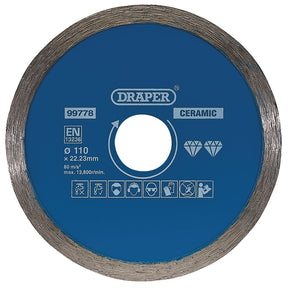 A blue circular ceramic cutting disc by Draper, identified as Draper Continuous Diamond Blade, 110mm - DBC1, with a 110mm diameter and 22.23mm bore, designed for angle grinders. It features various safety icons and specifications printed on the surface, making it ideal for cutting ceramic and natural stone tiles.
