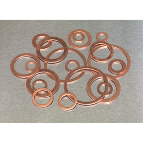 A Sealey Copper Sealing Washer Assortment 250pc - Metric (AB020CW) is scattered on a metal surface.