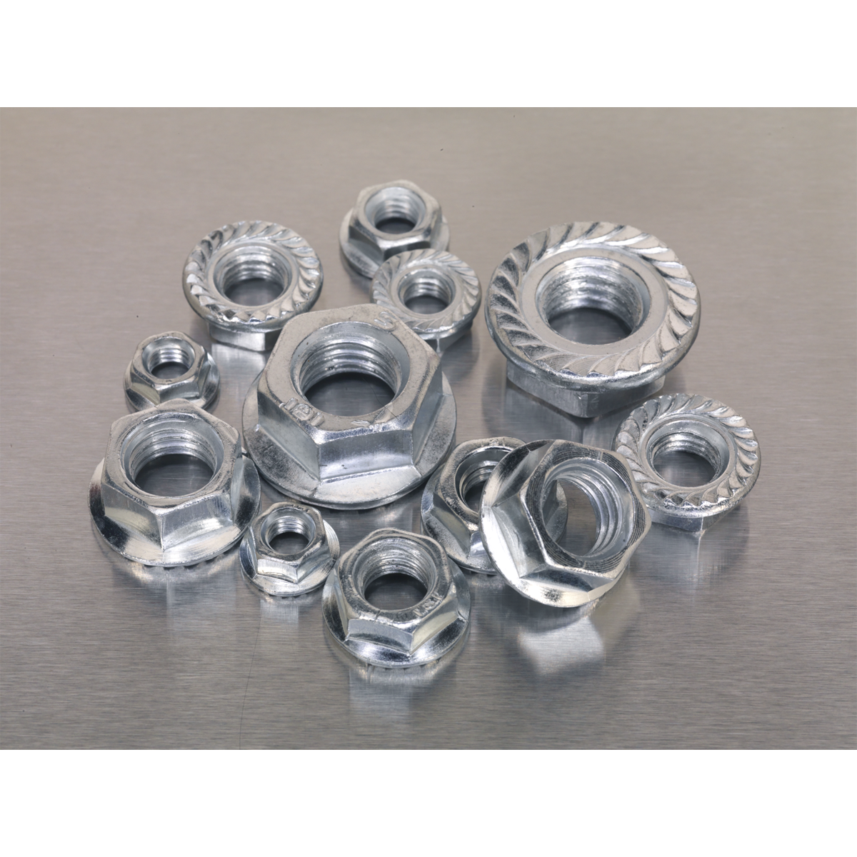 A collection of metallic nuts, including the Sealey Flange Nut Assortment 390pc M5-M12 Serrated Metric - AB031FN, displayed on a flat, reflective surface showcases an array of metric sizes conforming to DIN 6923 standards.