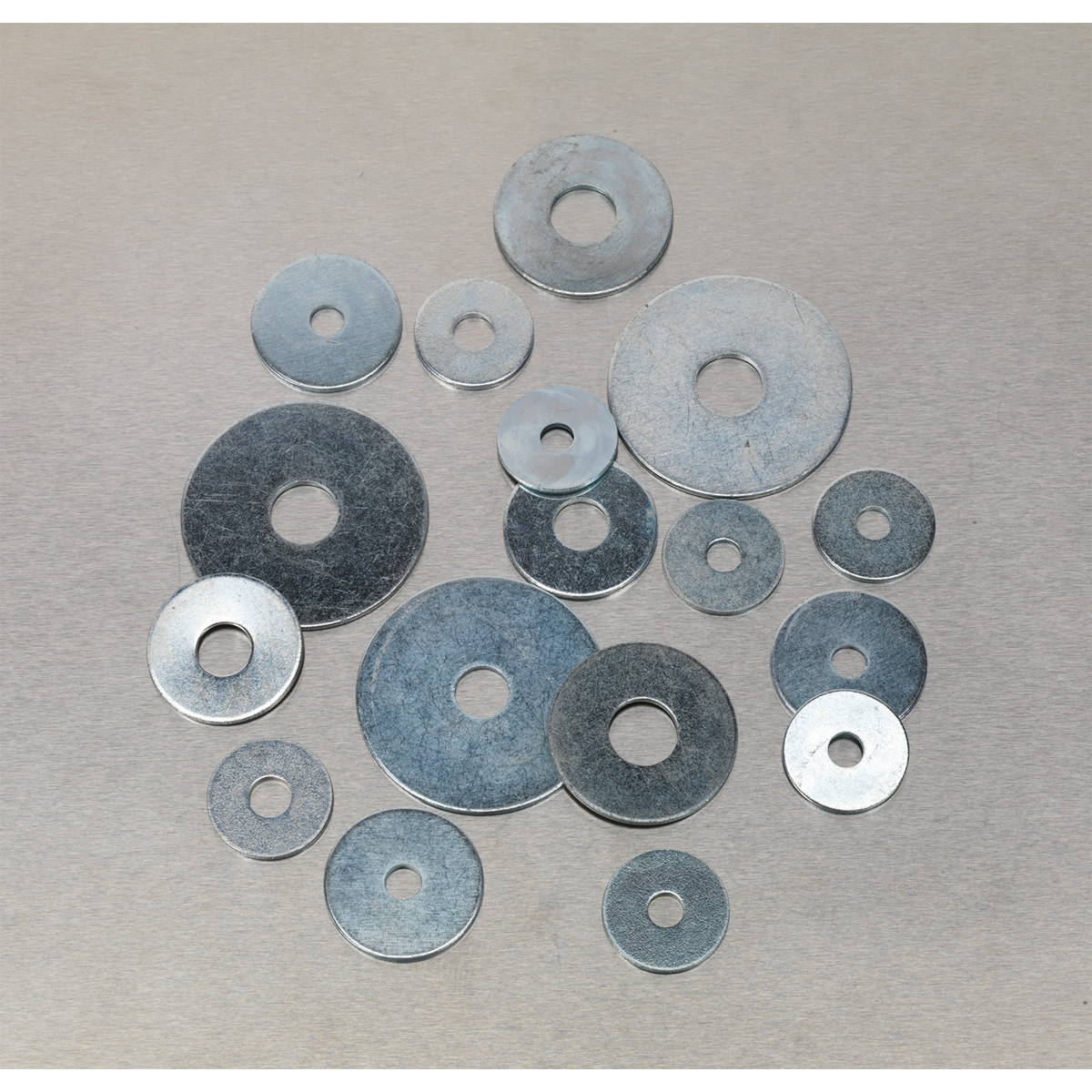 A group of variously sized metal washers, including the Sealey Repair Washer Assortment 240pc M5-M10 Metric Zinc Plated (AB059RW), arranged on a flat surface.