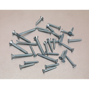 A pile of Sealey Self-Tapping Screws from the DIN 7982 510-piece Countersunk Pozi Zinc Assortment (AB062STCS) of varying lengths scattered on a light gray surface.