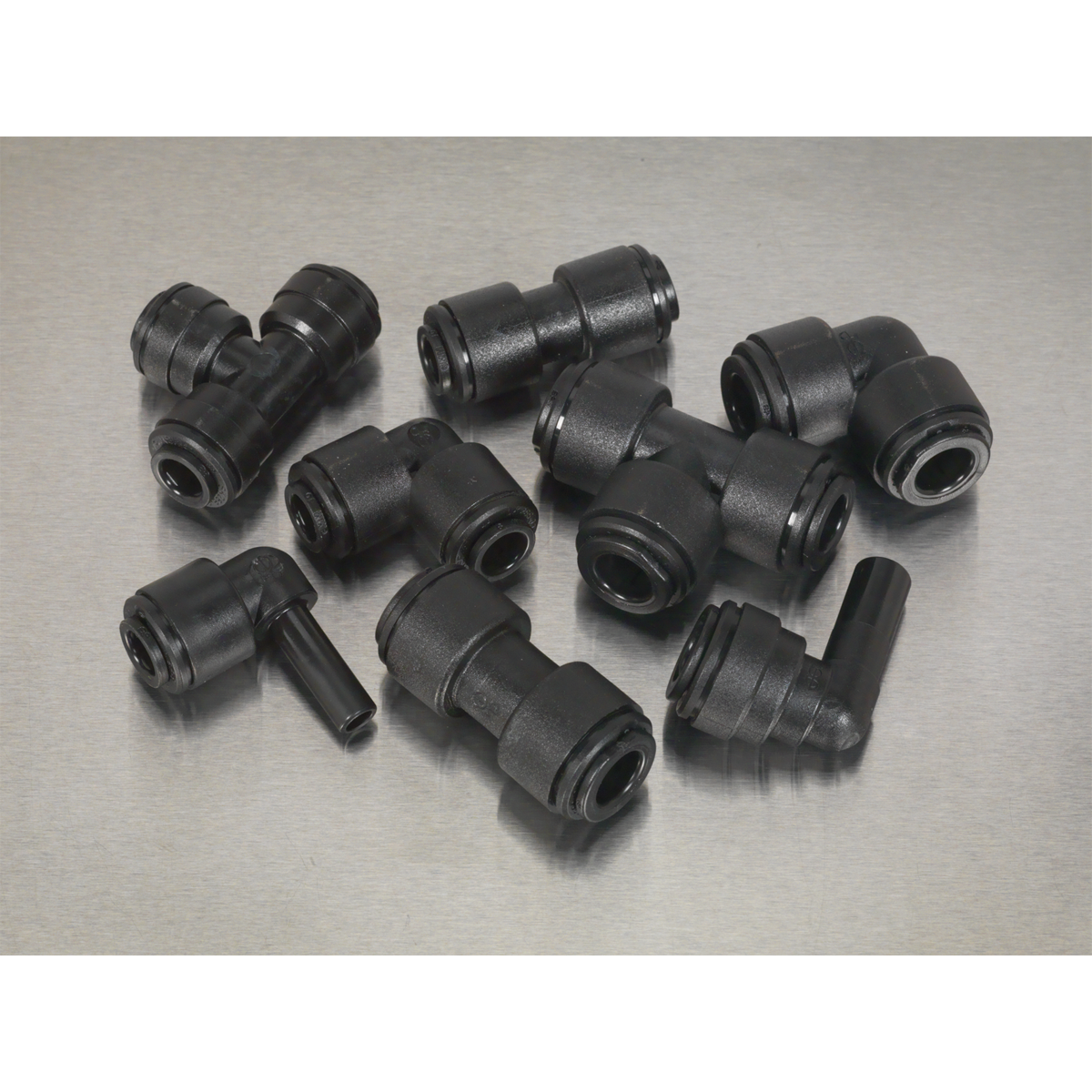 Several black plastic pipe fittings, including elbows and tees, are arranged on a gray surface, featuring Sealey Speedfit® Coupling Assortment 32pc Ø6 & Ø8mm Metric - AB069JG connectors for a secure fit.