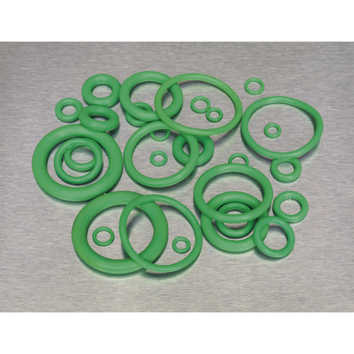 A collection of Sealey's Air Conditioning Rubber O-Rings, 225 pieces in various metric sizes, meticulously arranged on a gray surface. These green HNBR O-rings are ideal for automotive air conditioning systems using Freon R134a.