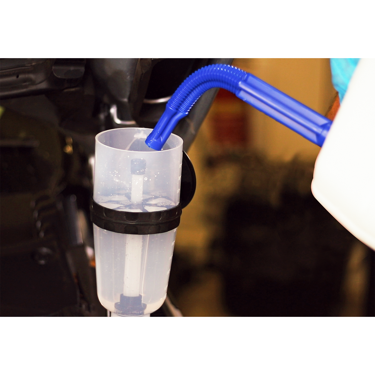 An AdBlue® Filling Funnel - Straight - ADB07S from Sealey, featuring a blue flexible spout, is inserted into a container. Water or clear liquid is being poured through the large capacity funnel.