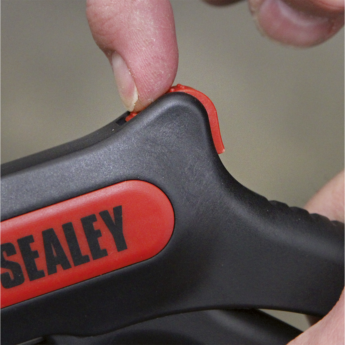 Close-up of a person using their thumb to press a red button on a Sealey Automatic Wire Stripping Tool - Pistol Grip - AK2265.