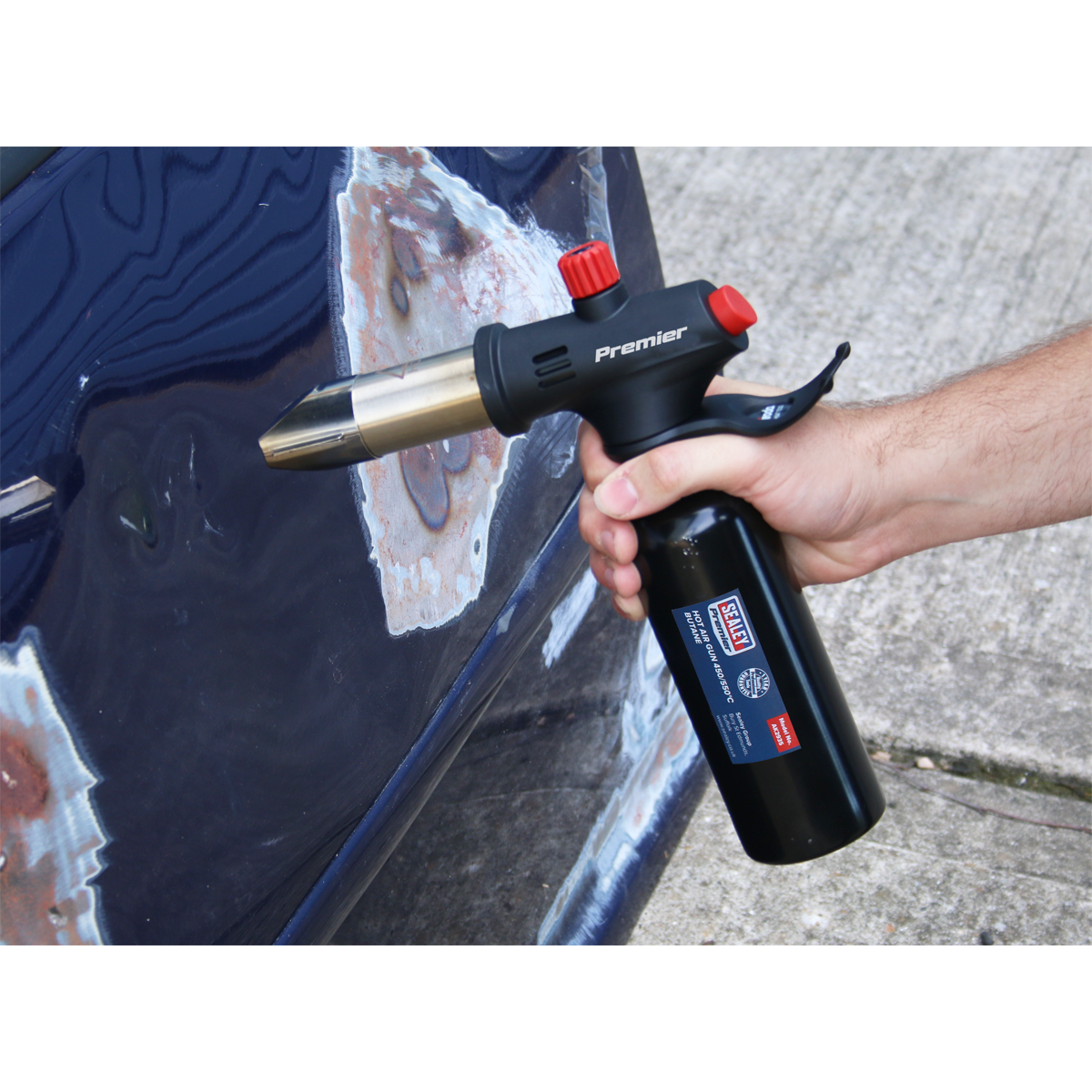 A person uses a Sealey Hot Air Gun 450/550°C - Butane - AK2935 on the body of a car with areas of stripped paint, making it perfect for various automotive applications.