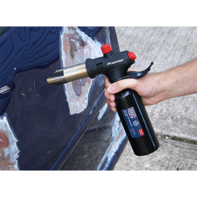 A person uses a Sealey Hot Air Gun 450/550°C - Butane - AK2935 on the body of a car with areas of stripped paint, making it perfect for various automotive applications.