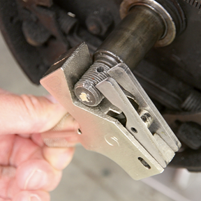 A close-up of a person's hand using the Sealey Adjustable Thread Restorer M4-M45 - AK314 to restore damaged threads on a metal component, possibly part of machinery or a vehicle.