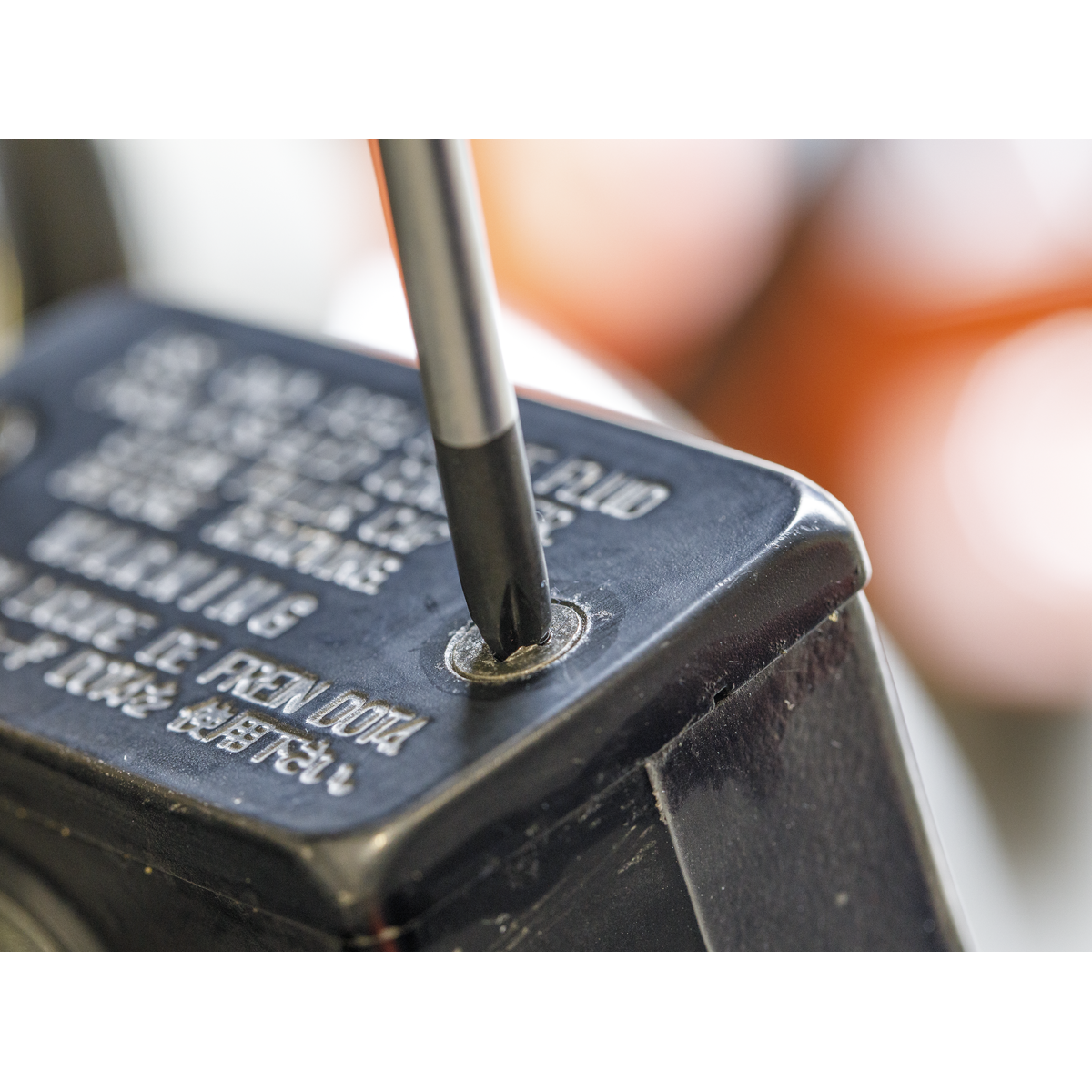 Close-up of the tip from the Sealey Screwdriver Set 4pc JIS - AK4314 inserted into a Japanese Industrial Standard screw on a black, metal surface. Text and warnings are partially visible on the surface.