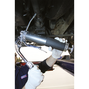 A person in white gloves uses the Sealey Grease Gun 2-Way Operating 3-Way Fill Heavy-Duty - AK48 to lubricate a machinery component.