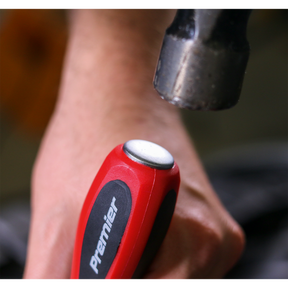 Close-up of a hand holding a red-handled screwdriver from the Sealey Screwdriver Set 6pc Hammer-Thru - AK4932, featuring a metal cap and Chrome Vanadium steel construction, with a hammer poised above it, indicating impact; this high-quality tool is supported by Sealey's lifetime guarantee.