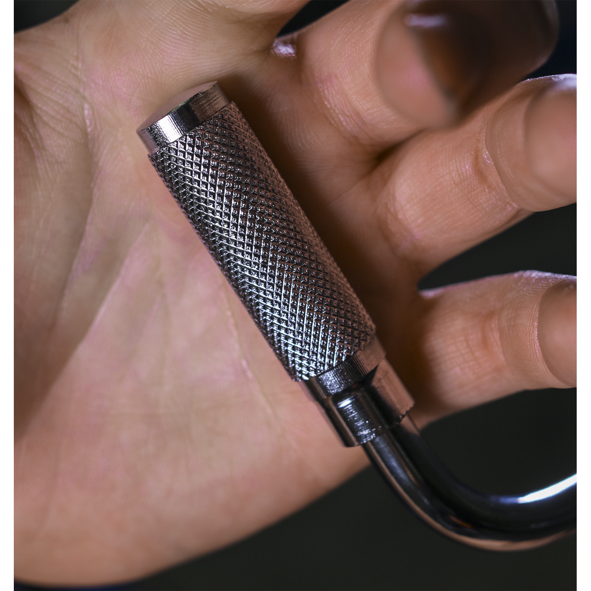 A hand holding a textured metallic cylinder made from Chrome Vanadium steel, with a curved hook attached at the bottom. This Speed Brace 3/8" Sq Drive - AK5694 by Sealey comes with a lifetime guarantee, ensuring durability and quality.