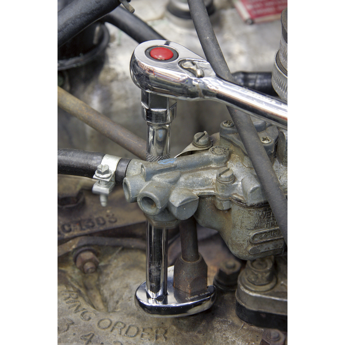 A close-up of a Sealey Crow's Foot Spanner from the 10-piece Metric set (AK598) being used to tighten a bolt on an engine part, with various hoses and mechanical components visible. Ideal for limited access applications, the Chrome Molybdenum steel enhances durability.